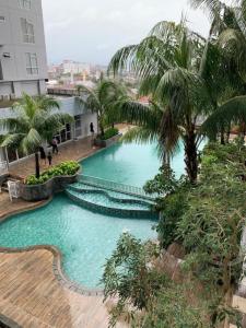 an overhead view of a large swimming pool with palm trees at Vida View Apartment by Vida Connect in Makassar