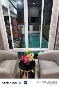 a room with two chairs and a table with flowers on it at Aroya Pool Villa Hatyai in Ban Thung Ri
