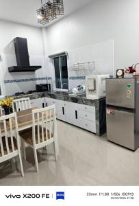 a kitchen with a table and a refrigerator at Aroya Pool Villa Hatyai in Ban Thung Ri