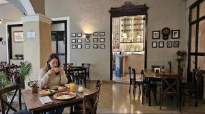 a woman sitting at a table with a cup of coffee at La Casa Rosa Imperial in Mérida