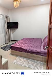 a bedroom with a bed with purple sheets and a tv at Aroya Pool Villa Hatyai in Ban Thung Ri +8 photos
