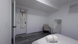 a white bedroom with a bed and a robe on a wall at Private Creekstone Basement Suite with Kitchen in Calgary +1 photo