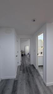 an empty living room with white walls and wood floors at Private Creekstone Basement Suite with Kitchen in Calgary