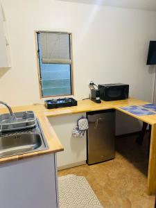 a kitchen with a desk with a sink and a window at Huahine Serenity Cottage in Maroe +11 photos