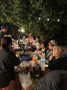 a group of people sitting at a long table at fishing inn beach house in Amami
