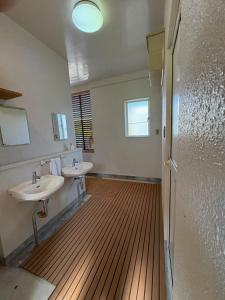 a bathroom with two sinks and a wooden floor at fishing inn beach house in Amami +31 photos