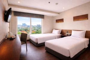 a hotel room with two beds and a window at BATIQA Hotel Darmo - Surabaya in Surabaya +25 photos