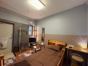 a small room with a bed and a desk and a television at fishing inn beach house in Amami