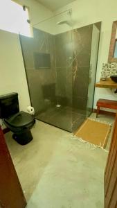 a bathroom with a glass shower with a toilet at Pousada Cordel de Itaúnas in Itaúnas