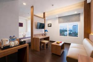 a living room with a couch and a television in a room at BATIQA Hotel Darmo - Surabaya in Surabaya
