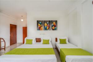two beds in a white room with a painting on the wall at Kandy City Oasis Hotel in Kandy