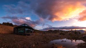 a glass house on the side of a mountain at Haurapa PurePod in Cromwell