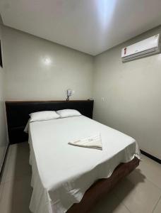 a bedroom with a white bed with a napkin on it at Ivan Pousada e Churrascaria Bode na Brasa in Feira de Santana