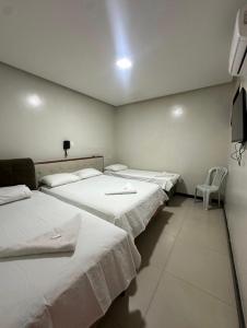 a room with three beds and a chair in it at Ivan Pousada e Churrascaria Bode na Brasa in Feira de Santana