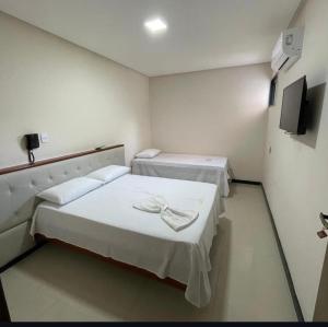 a room with two beds and a flat screen tv at Ivan Pousada e Churrascaria Bode na Brasa in Feira de Santana