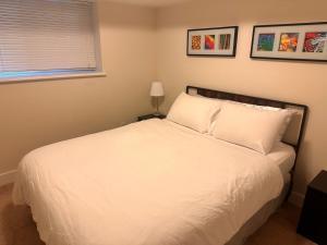 a bedroom with a bed with white sheets and a window at Albion Stay in Maple Ridge