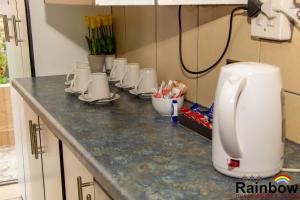 a kitchen counter with many cups on it at Rainbow Guest House and Tours in Uitenhage