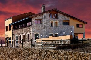 una casa de piedra en la playa con un cielo rojo en Hotel Restaurante Port d'Ager, en Àger