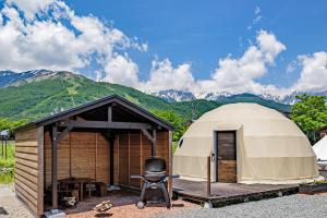a yurt with a chair in front of it with mountains at From P in Hakuba