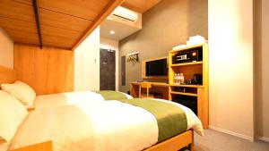 a bedroom with a bed and a desk and a television at Rita Hotel Namba in Osaka