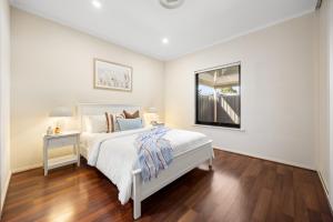 a white bedroom with a bed and a window at Gone Coastal - Family Beachside Breeze in Grange