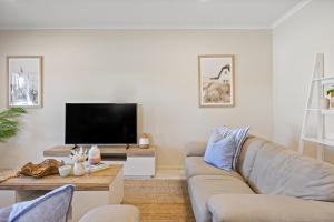 a living room with a couch and a tv at Gone Coastal - Family Beachside Breeze in Grange