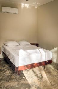 a bed with white sheets and pillows in a room at Apartamento Casa 24 in Bacalar