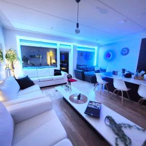 a living room with a white couch and a table at PENTHOUSE AUREA NORDIC Tasokas moderni kaupunki huoneisto Tampereen huipulla -ISO JACUZZI omalla KATTOTERASSILLA - AURINKOTUOLIT ja Aurinko odottaa Sinua - huikea maisema- - 10 HLÖ - in Tampere