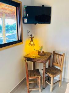 a wooden table and chair with a lamp and a window at Pouso Canastra - Chalés in São João Batista do Glória