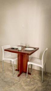 a wooden table with two white chairs around it at Apartamento Casa 24 in Bacalar