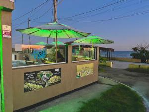 a food stand with green umbrellas on the beach at Pousada & Espaço Orlla 39 in Maricá