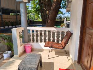 a chair sitting on a porch next to a tree at Sarovar Ashwem in Mandrem