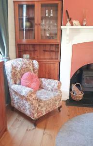 a chair with a pink pillow sitting in a room with a fireplace at Haven Cottage Kangaroo Island in Kingscote