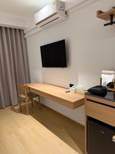 a room with a table and a television on the wall at 611 Hotel in Phetchaburi