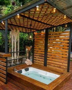 a hot tub in a deck with a wooden pergola at Omghat Glamping - Domo Sarasvasti in El Peñol