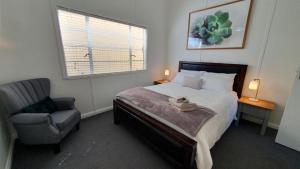a bedroom with a bed and a chair and a window at Haven Cottage Kangaroo Island in Kingscote