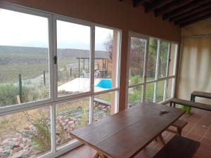 a room with a wooden table and large windows at Posada del Río 2 in Ciudad Lujan de Cuyo