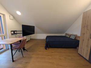 a bedroom with a bed and a desk and a television at LechApartments in Kaufering