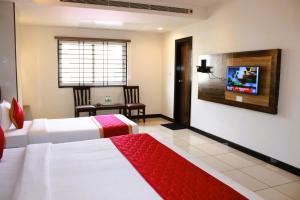 a hotel room with two beds and a flat screen tv at Mayuri Residency BTM Layout in Bangalore +23 photos