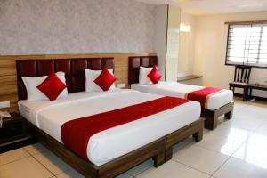a bedroom with two beds with red pillows at Mayuri Residency BTM Layout in Bangalore