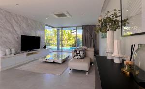 a living room with a tv and a couch and a chair at Maerim Luxury 3BR Pool Villa with Mountain View in Ban Tai