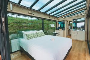 a bedroom with a bed in a room with windows at Rewarewa PurePod in Helensville
