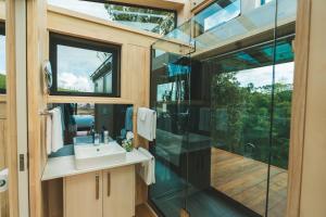 a bathroom with a sink and a glass shower stall at Rewarewa PurePod in Helensville +8 photos