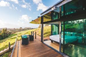a glass house with a bed on a deck at Rewarewa PurePod in Helensville