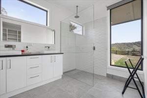 a bathroom with white cabinets and a glass shower at Eildon Valley Views in Eildon