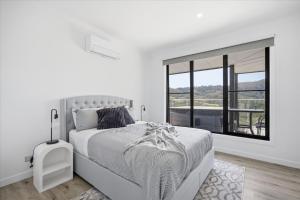 a white bedroom with a large bed and a window at Eildon Valley Views in Eildon