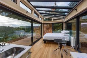 a bedroom with a bed in a glass house at Ruru PurePod in Waikino