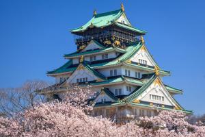 a japanese castle with cherry trees in front of it at Rita Hotel Namba in Osaka