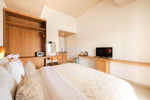 a bedroom with a white bed and a television at Cannella Suites Ubud - Ubud Center prime location in Ubud