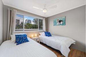 two beds in a room with a window at Seychelle unit 5 Kings Beach in Caloundra